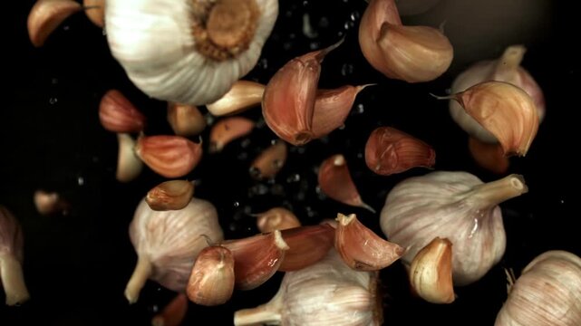 Garlic fly up and fall down on a black background. Filmed on a high-speed camera at 1000 fps. High quality FullHD footage
