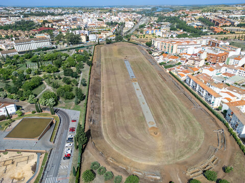 Aerial view of the ancient Roman Circus Maximus, a vast oval space contrasting with the modern city's architecture, reflecting history and urban life, Merida, Badajoz, Spain.