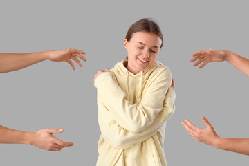 Young woman hugging herself and hands on grey background