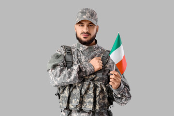 Young soldier with flag of Ireland on grey background