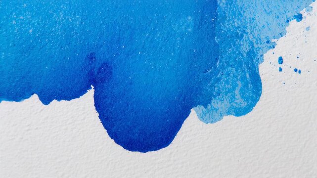 Spreading fresh blue pigment drop on textured paper, pooling and showing splatters while drying