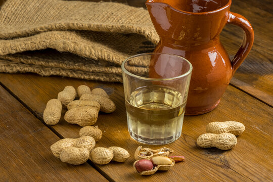 Cacahuetes, vaso de vino blanco y jarra de barro