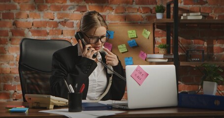 A woman in a business suit talks on two phones at the same time