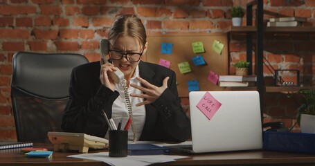 Stressed Businesswoman Yelling into Office Telephone