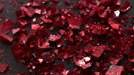 Zooming camera revealing glossy red faceted fragments on dark matte slab, showing glitter dust - Powered by Adobe