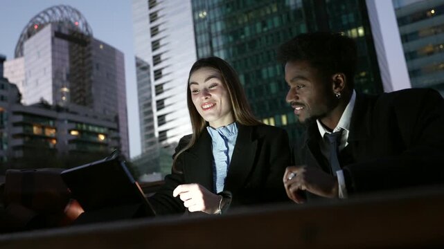 Happy diverse business colleagues celebrating success with tablet in city at night