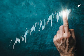 Hand pointing to rising financial chart symbolizing business growth and success
