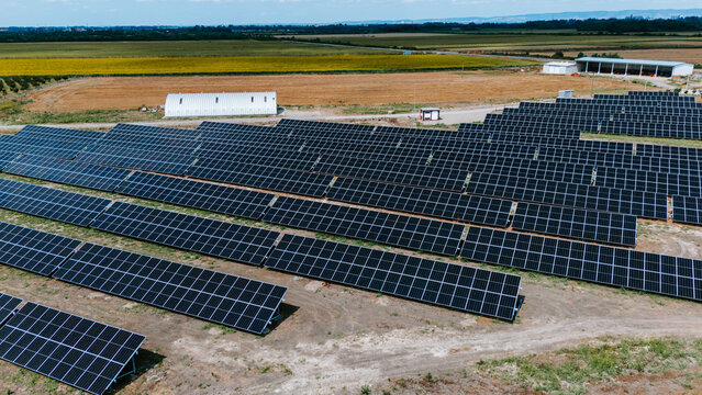 Aerial view of solar panels stretch across the landscape, contrasting against the golden fields and distant buildings, Belgrade, City of Belgrade, Serbia.
