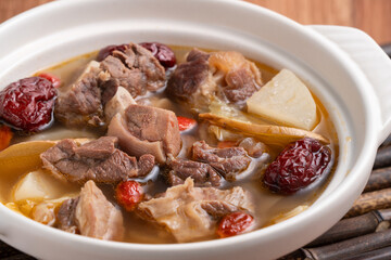 Traditional Chinese medicinal mutton hot pot with herbs in white bowl.
