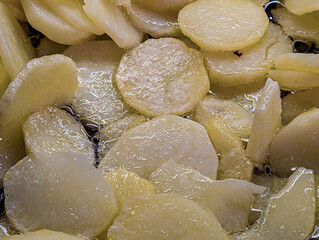 Detailed view of potato slices cooking in hot water or oil, creating a rich texture.