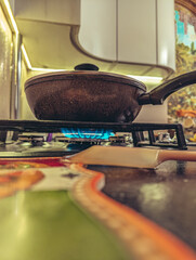 Cooking pan with lid heating on a gas burner with a bright blue flame in a kitchen setting.