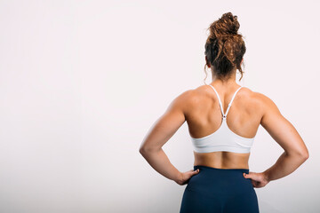 Obraz premium Woman showing strong back muscles in workout clothes