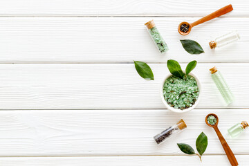 Obraz na płótnie Canvas Organic cosmetics products - tea tree essential oil and sea salt near green leaves top view