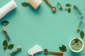 Naklejka na ściany i meble Spa pedicure accessories and organic cosmetics products - tea tree essential oil and sea salt near green leaves top view