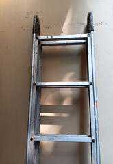 Close up of silver metal extension folding ladder isolated on yellow wall background.