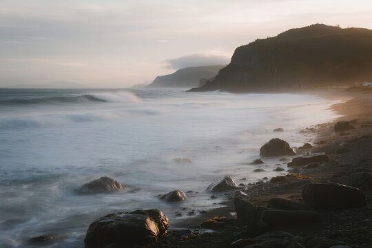 Coastal landscape with rocky shoreline and misty ocean waves at dawn