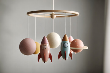 Colorful mobile featuring rockets and planets hangs in a stylish child's room, creating a whimsical atmosphere with soft lighting and a serene backdrop