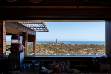 Coastal lighthouse view from a window on a sunny day