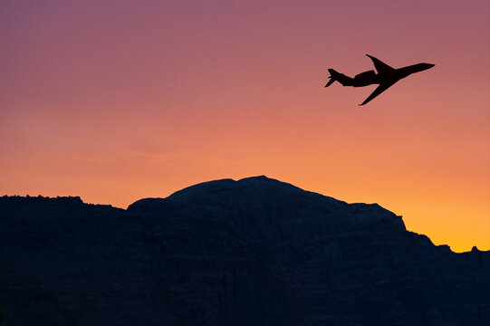 Private executive jet taking off over a mountain with a colourful sky at sunset