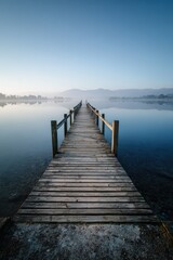Fototapeta premium Serene lakeside scene: straight pier and mirrored sky in calm water