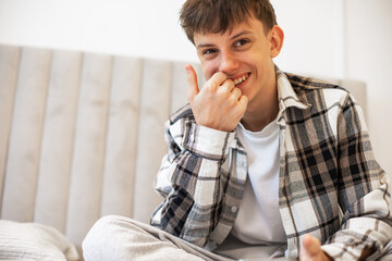 A teenage boy in a plaid shirt lies on his bed and studies with textbooks and notebooks, focusing on his homework. A natural lifestyle scene showing everyday student life and learning at home.