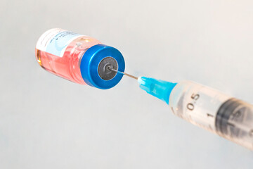 Vaccine in vial with syringe on blue background