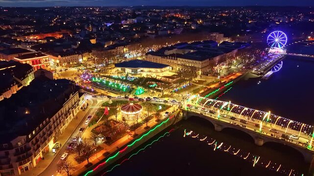 Drone arc over Laval&rsquo;s Christmas lights, showing Pont Aristide Briand, the Ferris wheel, reflections on the Mayenne, the funfair and festive streets.
