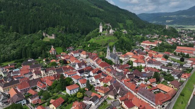 Summer drone footage showing medieval Friesach, old fortified walls, rooftops, towers, hills, serene atmosphere, warm daylight, gentle cinematic motion