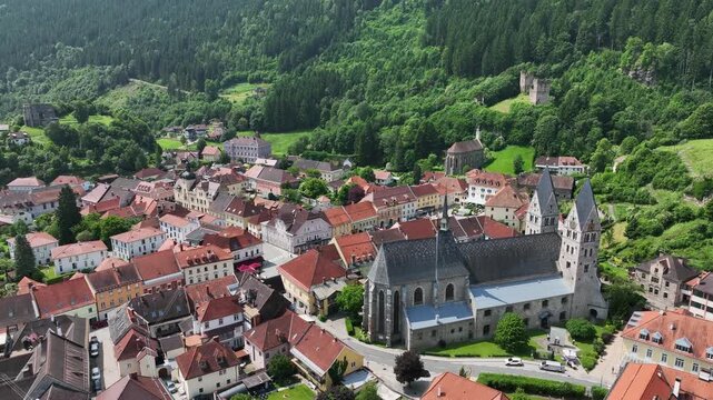 Summer drone footage showing medieval Friesach, old fortified walls, rooftops, towers, hills, serene atmosphere, warm daylight, gentle cinematic motion