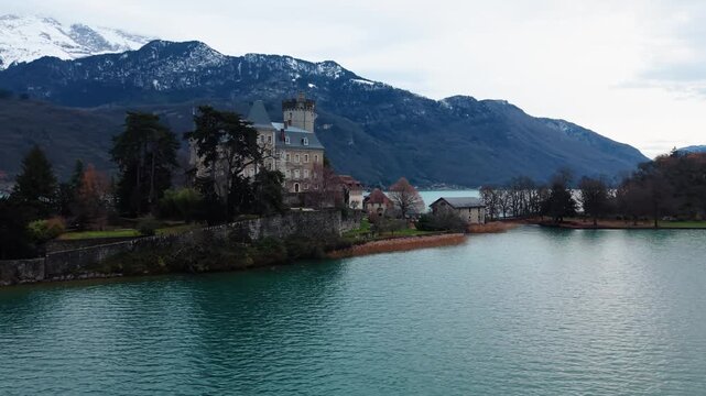 Aerial view of Chateau de Duingt, a medieval castle standing proudly by the lake with snow-capped mountains in the background, Duingt, Auvergne-Rhone-Alpes, France.