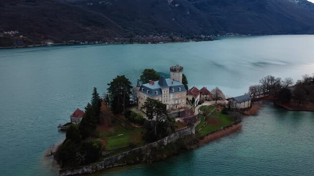 Aerial view of Chateau de Duingt, a historic castle nestled on a small island in the lake, surrounded by calm turquoise waters, Duingt, Auvergne-Rhone-Alpes, France.