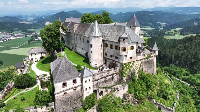 Cinematic drone footage capturing Hochosterwitz Castle on hilltop, fortified walls, dramatic cliffs, summer colors, sweeping aerial movement, historical landmark atmosphere