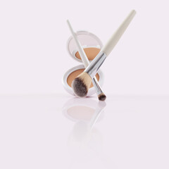 Opened compact powder, blusher with makeup brushes on Glossy Surface