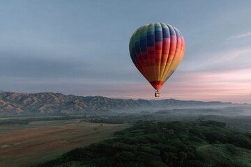 Obraz premium A colorful hot air balloon floating above a lush landscape.