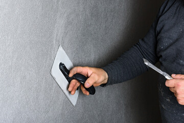 Worker using a float to smooth decorative pebble plaster on a wall.