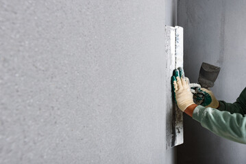 Applying concrete pebble plaster kornik using putty knife.