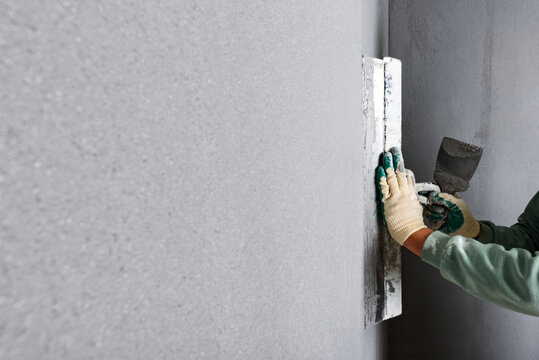 Applying concrete pebble plaster kornik using putty knife.