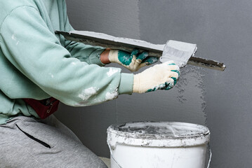 Applying concrete pebble plaster kornik using putty knife.