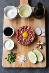 Raw steak tartare ingredients arranged neatly on board