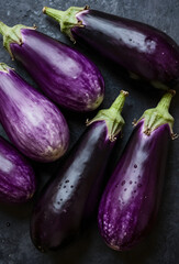 Vibrant eggplants arranged on dark surface