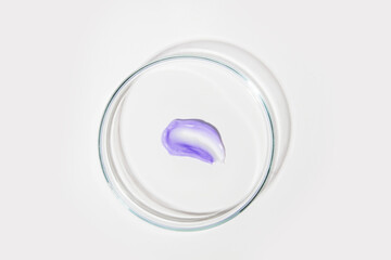 Petri dish with purple liquid smear on light background