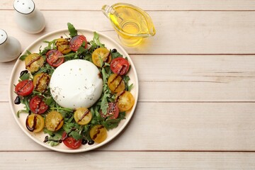 Delicious burrata cheese with arugula, tomatoes and dressing on wooden table, flat lay. Space for text