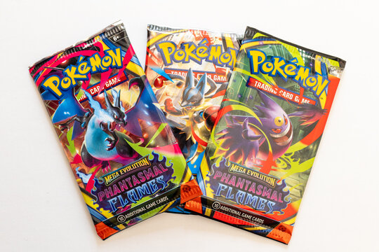 Bradford, UK - Dec 4 2025 - Collection of vibrant and shiny Pok&eacute;mon trading card game packs shot isolated on a white paper background. Includes Phantasmal Flames and Mega Evolution packs.