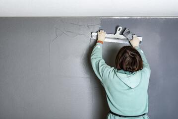 Applying concrete pebble plaster kornik using putty knife.