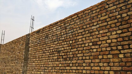 Old house roof with red tile pattern, brick chimney, and blue sky in the background