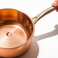 Close-up of hammered copper saucepan surface with unique dimpled texture, warm highlights on stark white background, minimalist and striking composition