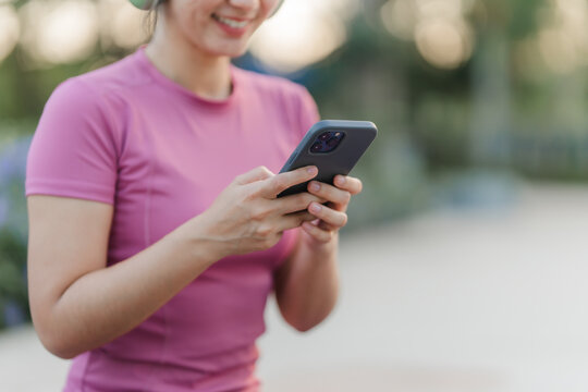 Digital Bliss: A woman, engrossed in her phone, exudes a sense of peace and pleasure, listening to music and enjoying a relaxing moment outdoors.