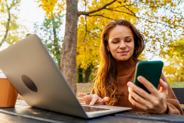 Freelancer woman with laptop and smartphone in outdoor workspace