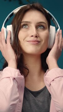 A young woman listens to music while relaxing at home She wears headphones and smiles