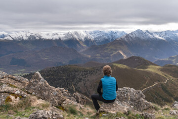 Mountaineer sitting on a mountaintop contemplating the snow-capped peaks